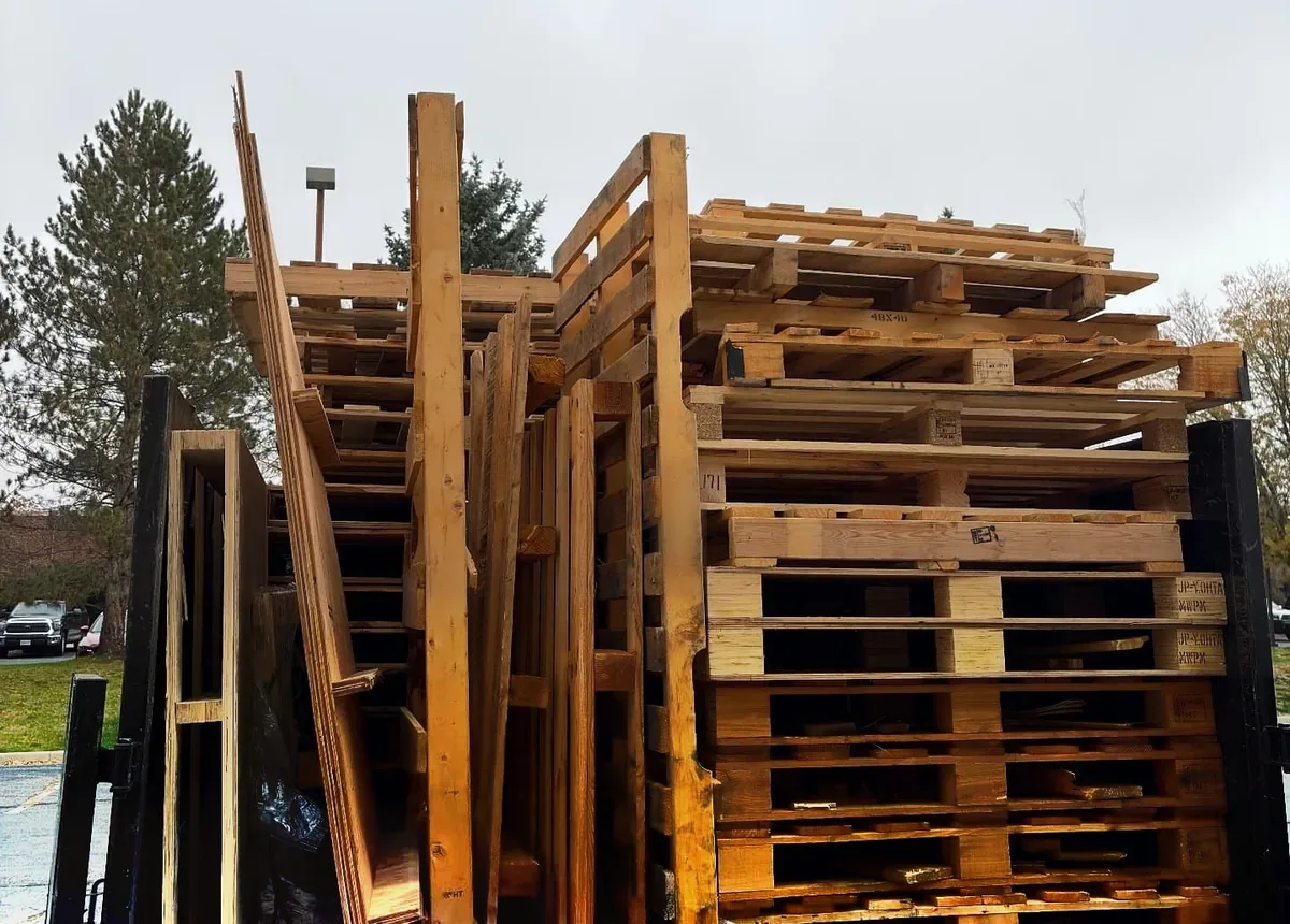 Rear view of a Junk Hand dump truck bed loaded high with stacked wooden pallets, skids and lumber after commercial pallet removal at a Boulder, Colorado business